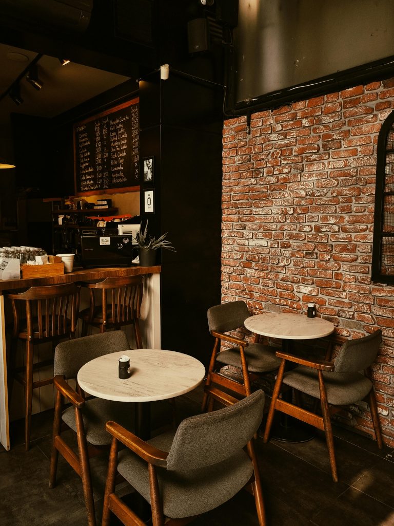 A warm and inviting café setting with a brick wall and wooden furniture, perfect for a tranquil coffee break.