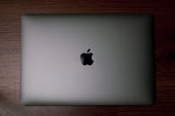 Minimalist flatlay of a closed MacBook on a wooden surface, perfect for tech and workspace themes.