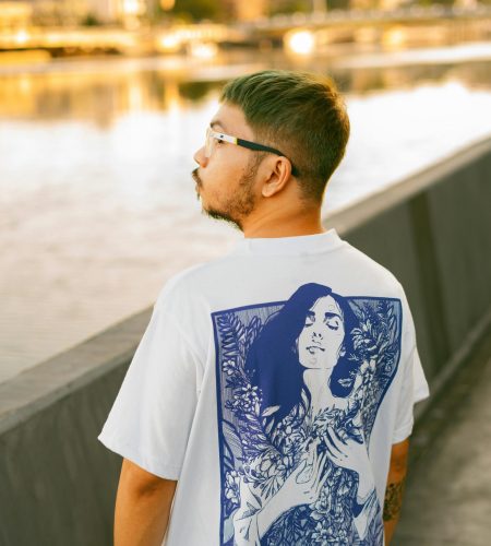 A stylish man wearing an artistic t-shirt beside Pasig River in Manila during a sunny day.