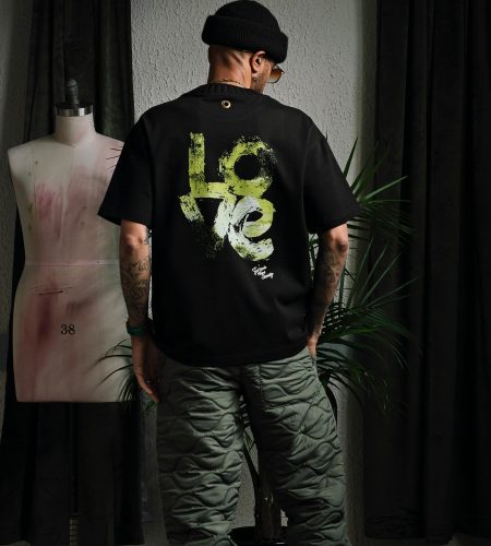 Man in trendy fashion ensemble featuring a black Love tee and quilted pants.